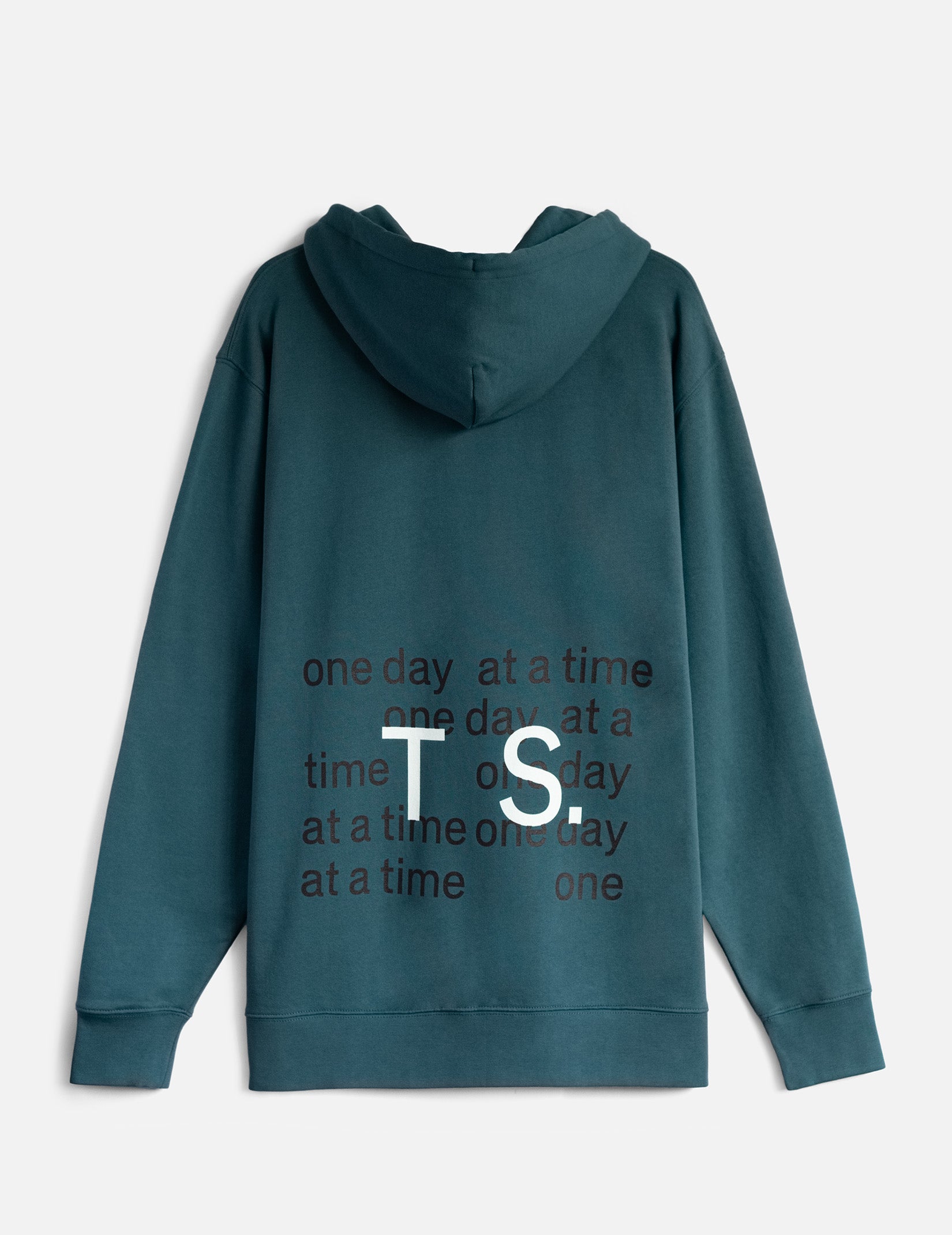 A teal colour hoodie viewed from the back, with a black print that says ‘one day at a time’ repeatedly. On top of this the letters TS (large, in white) are overlaid.