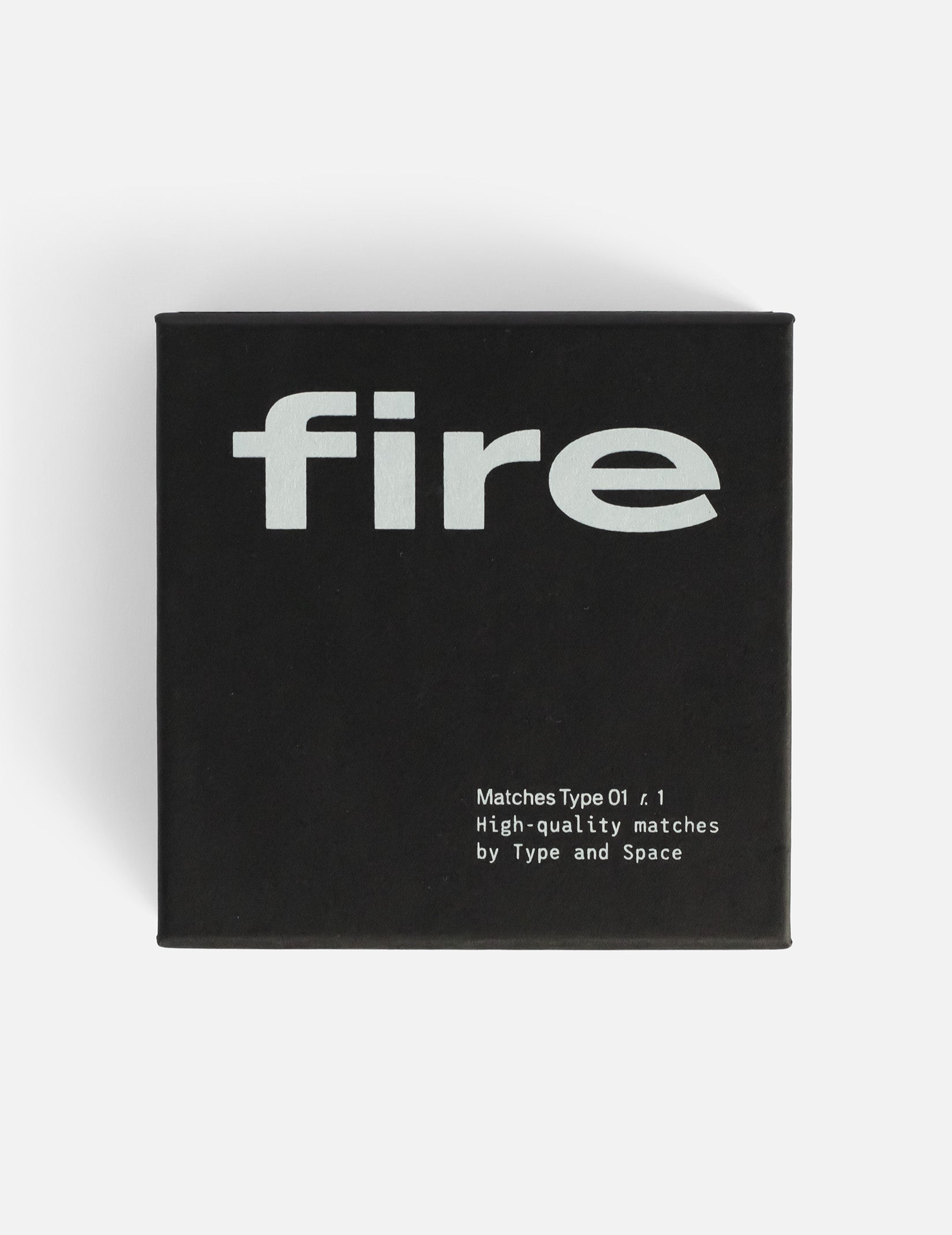 Large square black matchbox. Print that says 'Fire' in large letters and 'Matchbox Type 01 r1, high-quality matches by Type and Space' in small letters