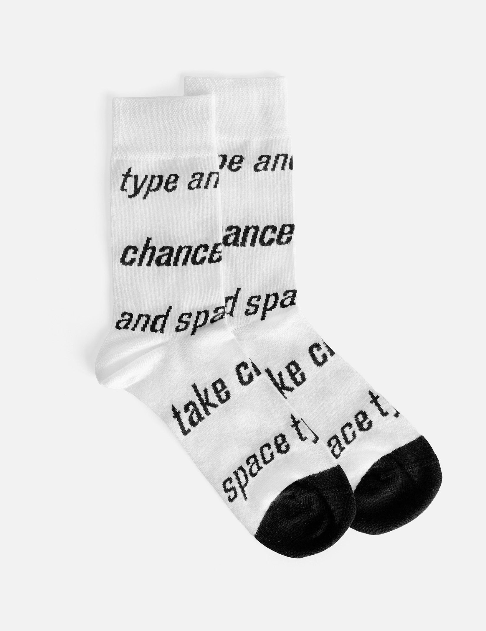 White socks with black typography in the shape of stripes that say ‘take chances’ and ‘type and space’. 