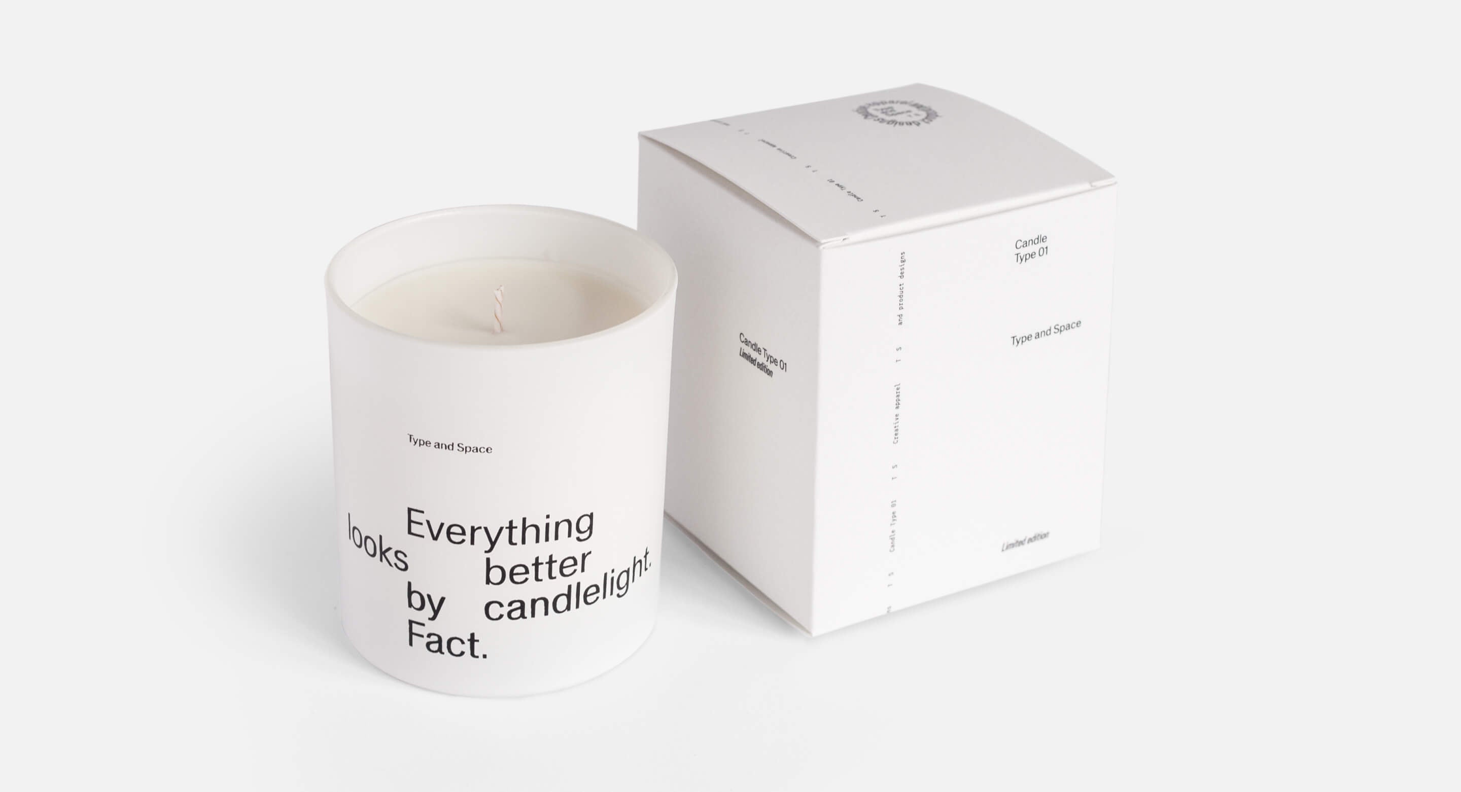 Closeup of a white candle and white box. The candle has a large print that says 'Everything looks better by candlelight. Fact.'